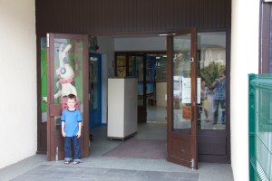Levi in front of his school on our first visit there. Amelia's classroom is the blue door just inside.